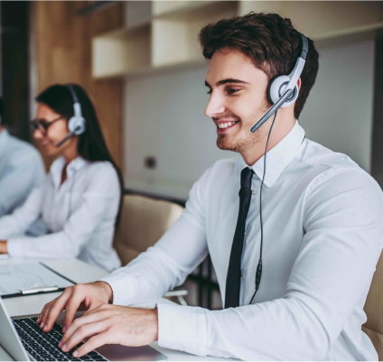 Ein lächelnder Support-Mitarbeiter mit Headset blickt auf seinen Laptop.